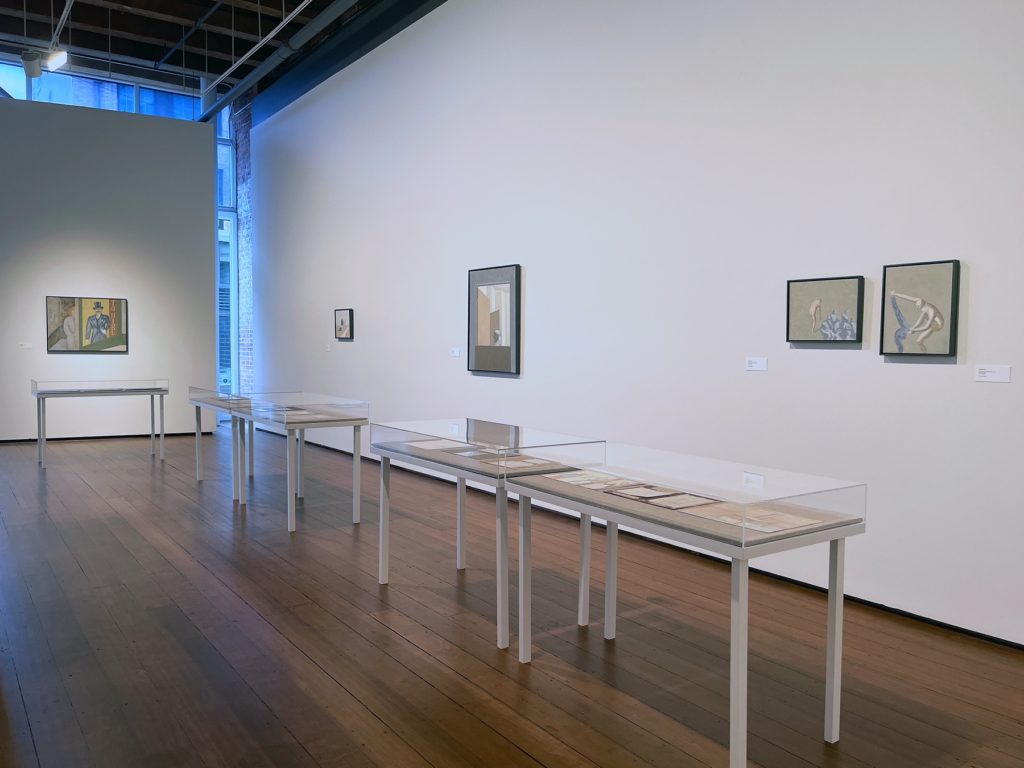installation view with table and paintings on wall